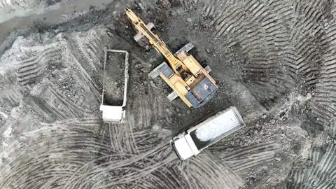 Aerial view of an excavator loading soil into trucks on a huge construction site Stock Footage 232588390