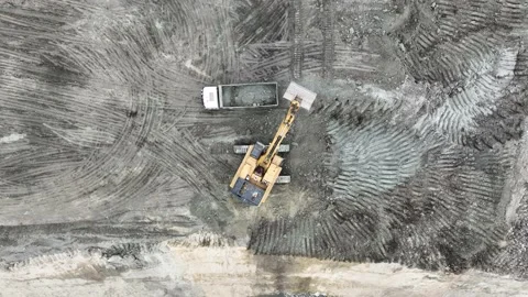 Aerial view of an excavator loading soil into trucks on a huge construction site Stock Footage 232588522