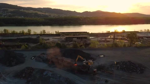 Aerial view of an excavator processing hot slag at sunrise by a river Video stock 342589660