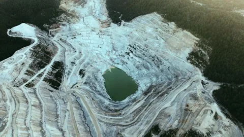 Aerial view of an expansive open-pit mining operation nestled in a forested Stock Footage 292947517