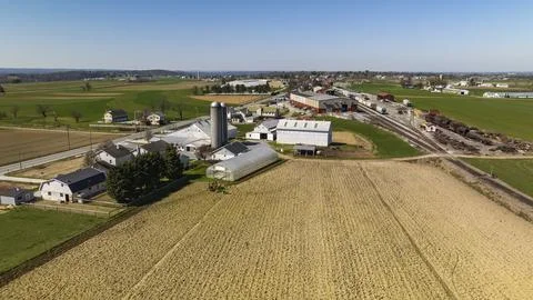 Aerial View Of A Farm Complex With Multiple Barns, Silos, And Plowed Fields In A Stock Photos