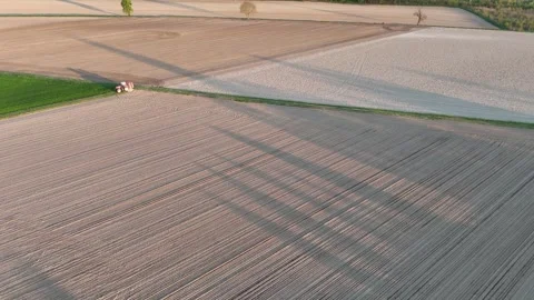 Aerial view of farm fields with tractor, wind turbine shadows, geometric crop Stock Footage 320604897