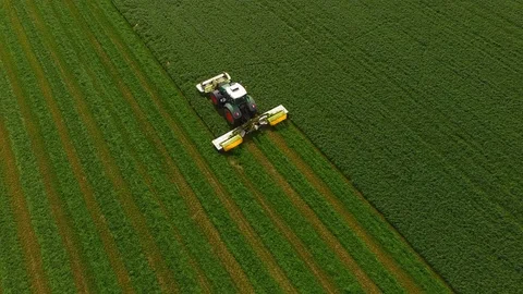 Aerial view of a farmer in a modern tractor mowing a green fresh grass field. Stock Footage 89442497