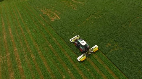 Aerial view of a farmer in a modern tractor mowing a green fresh grass field. Stock Footage 89443287