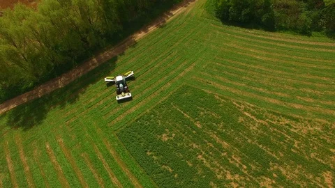 Aerial view of a farmer in a modern tractor mowing a green fresh grass field. Stock Footage 89467273