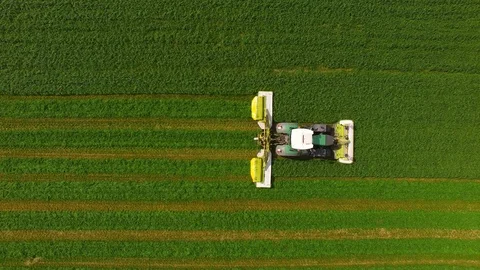Aerial view of a farmer in a modern tractor mowing a green fresh grass field. Stock Footage 89481735