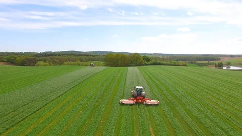 Aerial view of a farmer in a modern tractor mowing a green fresh grass field. Stock Footage 89486842