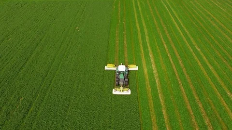 Aerial view of a farmer in a modern tractor mowing a green fresh grass field. Stock Footage 89515080
