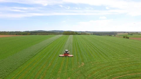 Aerial view of a farmer in a modern tractor mowing a green fresh grass field. Stock Footage 89515944