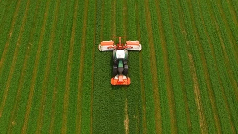 Aerial view of a farmer in a modern tractor mowing a green fresh grass field. Stock Footage 89518479