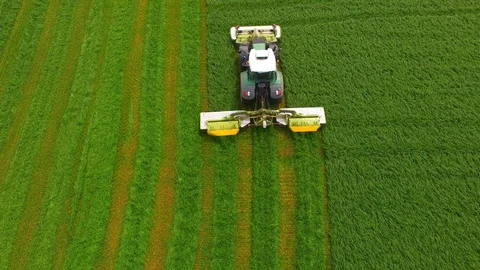 Aerial view of a farmer in a modern tractor mowing a green fresh grass field. Stock Footage 89520104