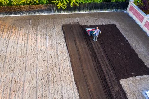Aerial view of Farmer plows the garden with a cultivator, preparing it for pl Stock Photos