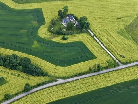 Aerial view of farmhouse surrounded by patchwork crop fields and winding co.. 스톡 사진