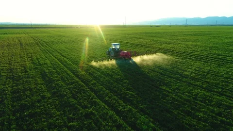 Aerial view of farming tractor plowing and spraying on field Stock Footage