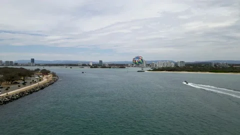 Aerial view of a fast boat pulling a parasail through the air with a city Stock Footage 145566581