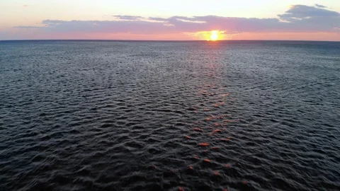 Aerial view, fast flight towards the sun over calm sea Stock Footage 126352127