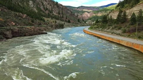 Aerial view of fast flowing river next to mountain highway with traffic Stock Footage 343543340