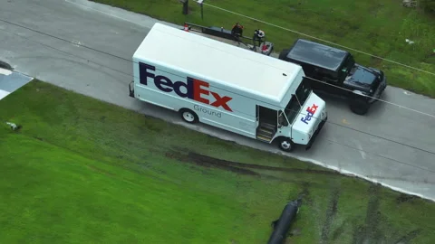Aerial view of Fedex white delivery truck driving on suburban street delivering Stock Footage 308400899