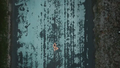 Aerial view of female runner sprinting down textured paved countryside road Stock Footage 339624327
