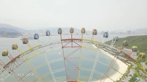 Aerial view ferris wheel in amusement park on sea, mountain and modern city Stock Footage 106989181