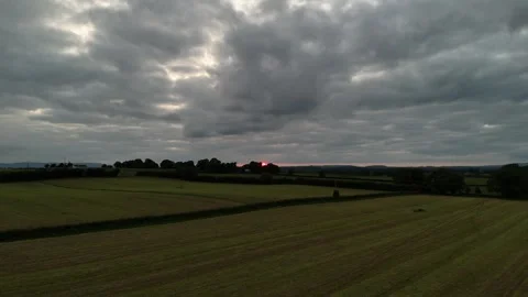 Aerial View of Field at Sunset Under Dramatic Cloudy Sky in 4K Stock Footage 333334114