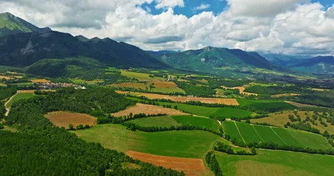 Aerial view of fields and sun in the sky with mountains in the background Stock Footage 328102466