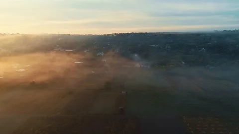 Aerial view of fields with clouds above them and a green village. Stock Footage 113382227
