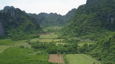 Aerial view fields surrounded by rocky hills with trees Stock Footage 102929774