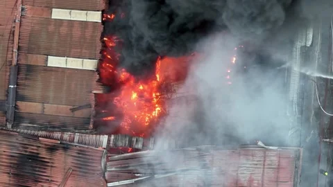 Aerial view fire is burning in a building and firefighters 스톡 동영상 329349118