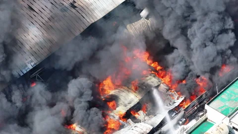 Aerial view of Fire in industrial building. Multi-storey concrete hangar with fl Vidéo 246726440