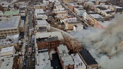 Aerial View Firemen fight a blazing house fire with water high pressure hose 4K Stock Footage