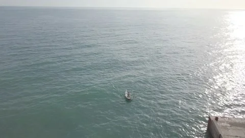 Aerial view fisherman rowing oars in boat in open sea. Sunlight glares on water Stock Footage 139264853