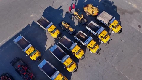 Aerial view of a fleet of yellow construction dump trucks parked in a lot Stock Footage 338191396