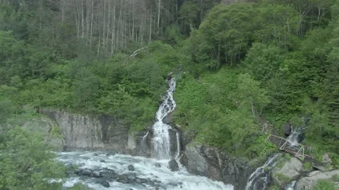 Aerial view flight over a swift mountain river with a stormy waterfall. Video stock 156346918