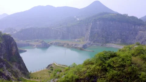 Aerial view of a flooded mountain quarry with turquoise water and winding paths Stock Footage 342090657