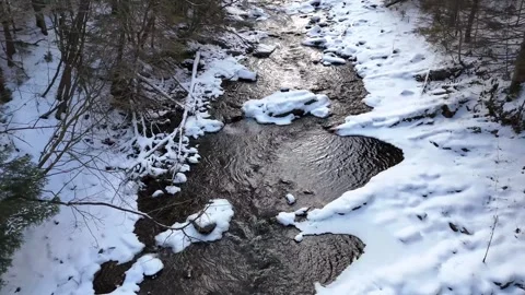 Aerial view of flowing stream through snow-covered landscape showcasing the Stockbeeldmateriaal 348201227