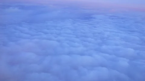 Aerial view of fluffy clouds from an airplane window at dusk in 4k slow motion Stock Footage 264769595