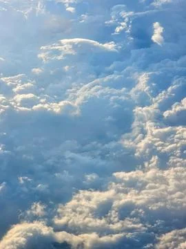Aerial view of fluffy clouds from a flight window with sunlight illuminatin.. Stock Photos