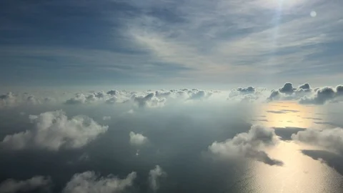Aerial view of fluffy cloudy sky with an ocean below, serene sunrise Stock Footage 121945800