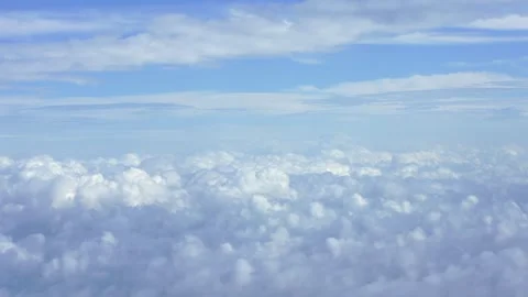 Aerial view of fluffy white clouds with a hint of Earth horizon during a flight Stock Footage 310853717