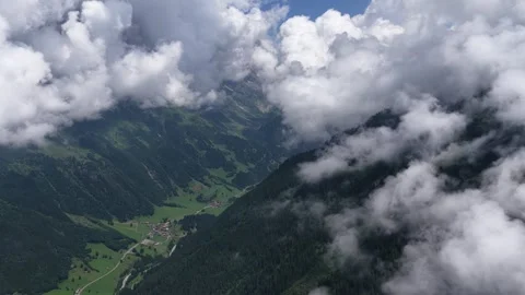Aerial view flying above clouds over alpine valley Stock Footage 317656289