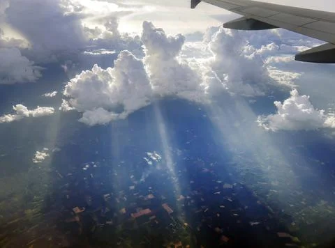 Aerial view flying above dramatic fluffy clouds and sun rays piercing shini.. Stock Photos