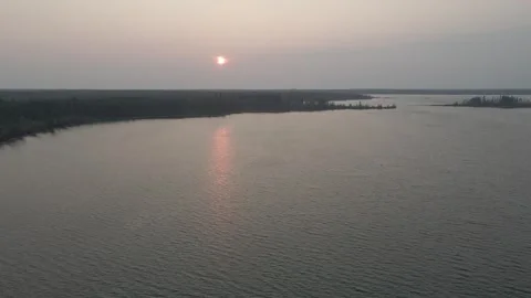 Aerial view flying above a large lake that is surrounded by a thick forest  Stock Footage 275410208