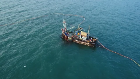 Aerial view. Flying around an old wooden fishing ship in the sea at sunset.  動画素材 101990978