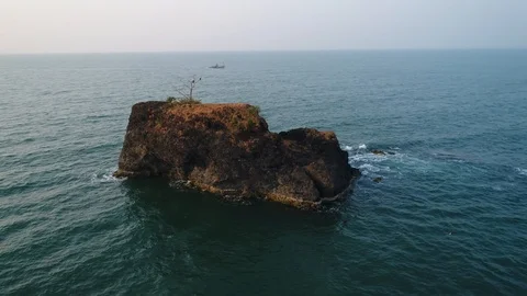 Aerial view. Flying around a small rocky uninhabited island in the sea at sunset 스톡 동영상 101987333