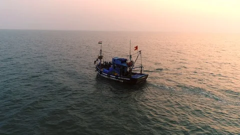 Aerial view. Flying around a small fishing vessel at sunset over the sea.  Stock Footage 104667720