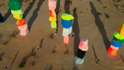Aerial view flying away from stacked colorful rainbow artwork in desert Stock Footage 91104591