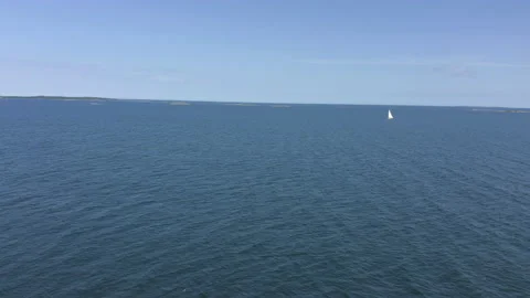 Aerial view flying backward over open sea, remote island with washed lighthouse Stock Footage 134178883