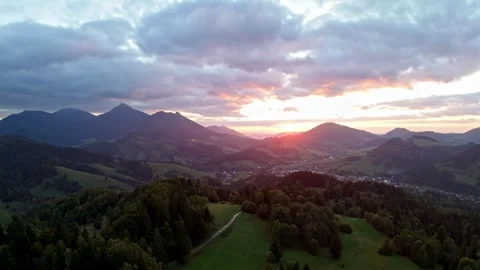Aerial view flying backward over mountain valley during sunset with dramatic Stock Footage 321075956