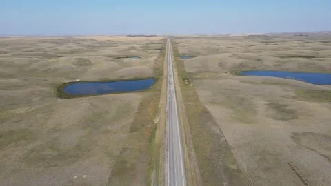 Aerial view flying forwards over a vast open grassland prairie that is cut by a  Stock Footage 275409417
